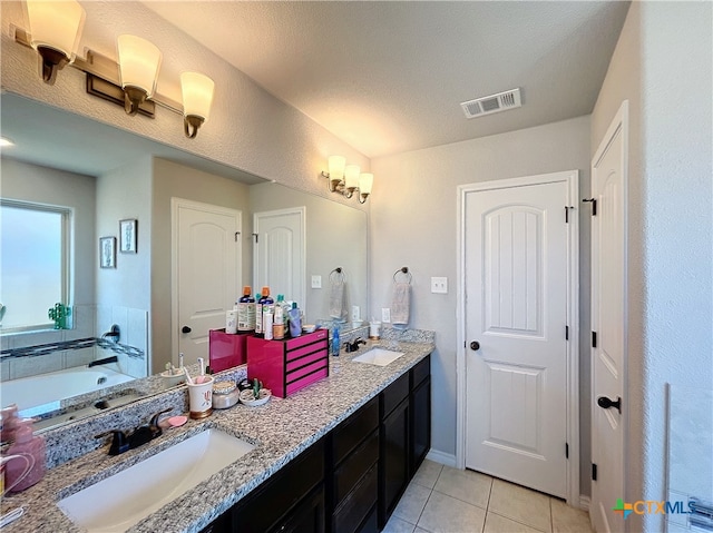 bathroom with tile patterned flooring, vanity, a textured ceiling, and a bath