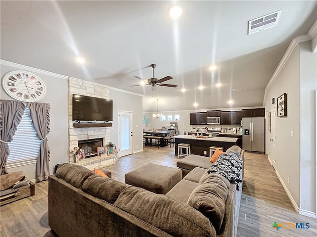 living room featuring light hardwood / wood-style floors, sink, ceiling fan, crown molding, and a fireplace