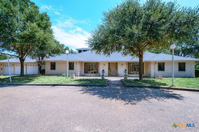 single story home with covered porch, a garage, and a front yard