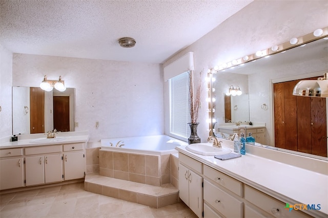 bathroom featuring vanity, a textured ceiling, and tiled bath