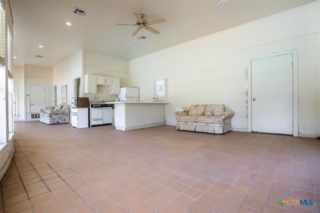 kitchen with white refrigerator, kitchen peninsula, ceiling fan, light tile patterned floors, and white cabinetry