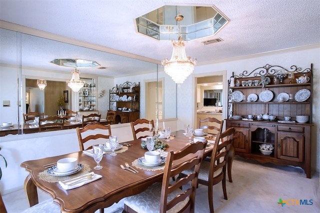 dining room with ornamental molding, a textured ceiling, and a chandelier