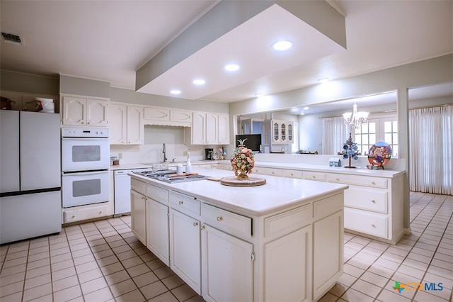 kitchen with white appliances, light tile patterned floors, a center island, and a chandelier