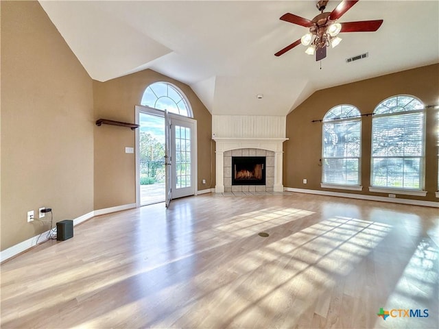 unfurnished living room featuring ceiling fan, a tile fireplace, light hardwood / wood-style flooring, and lofted ceiling