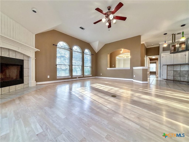 unfurnished living room with ceiling fan, lofted ceiling, light hardwood / wood-style floors, and a tiled fireplace