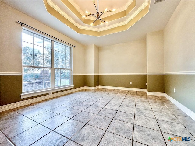 spare room featuring an inviting chandelier, tile patterned floors, a tray ceiling, and ornamental molding