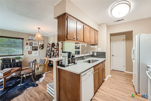 kitchen featuring sink, a textured ceiling, decorative light fixtures, white appliances, and light wood-type flooring