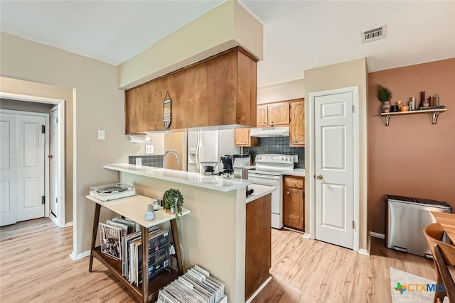 kitchen featuring electric stove, kitchen peninsula, decorative backsplash, and light hardwood / wood-style flooring