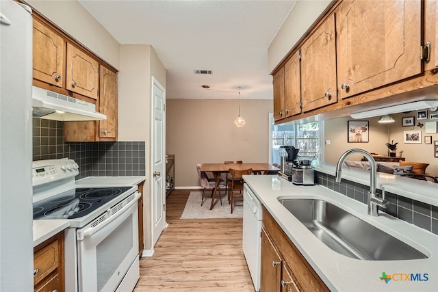 kitchen with backsplash, hanging light fixtures, sink, white appliances, and light hardwood / wood-style flooring