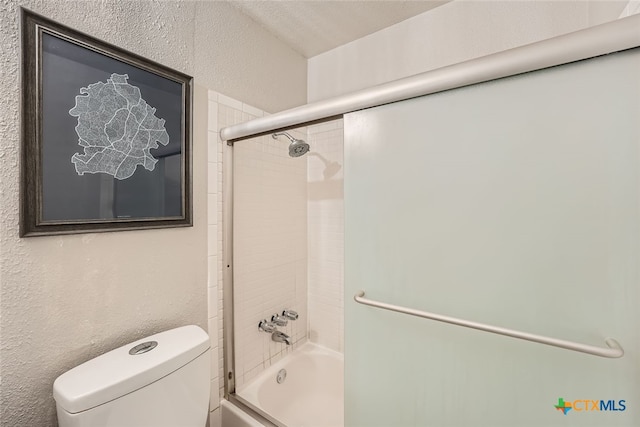 bathroom featuring shower / bath combination with glass door, a textured ceiling, and toilet