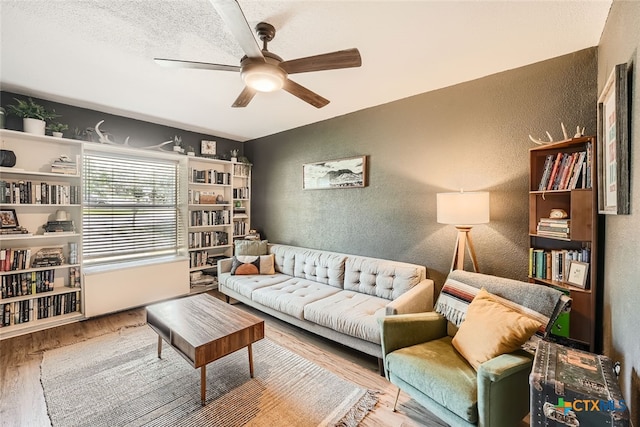 living room with wood-type flooring, ceiling fan, and a textured ceiling