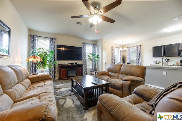 living room with light hardwood / wood-style floors and ceiling fan with notable chandelier