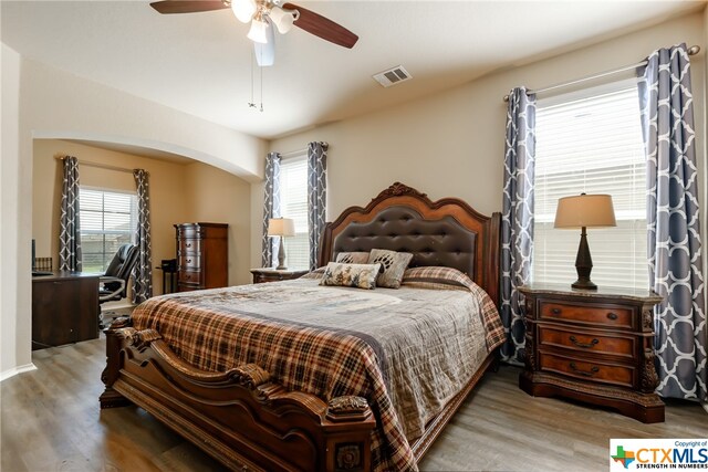 bedroom with hardwood / wood-style floors, multiple windows, and ceiling fan