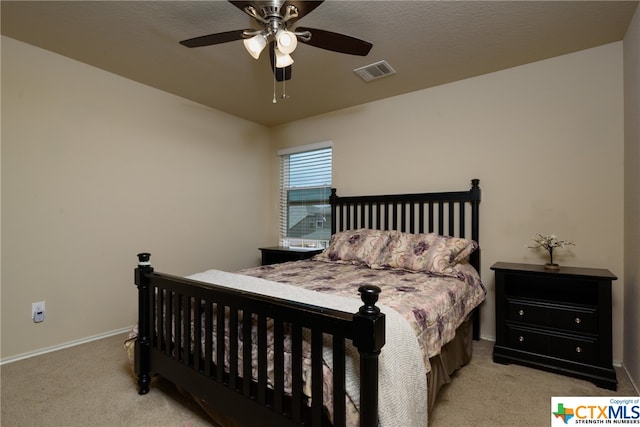 carpeted bedroom featuring ceiling fan and a textured ceiling