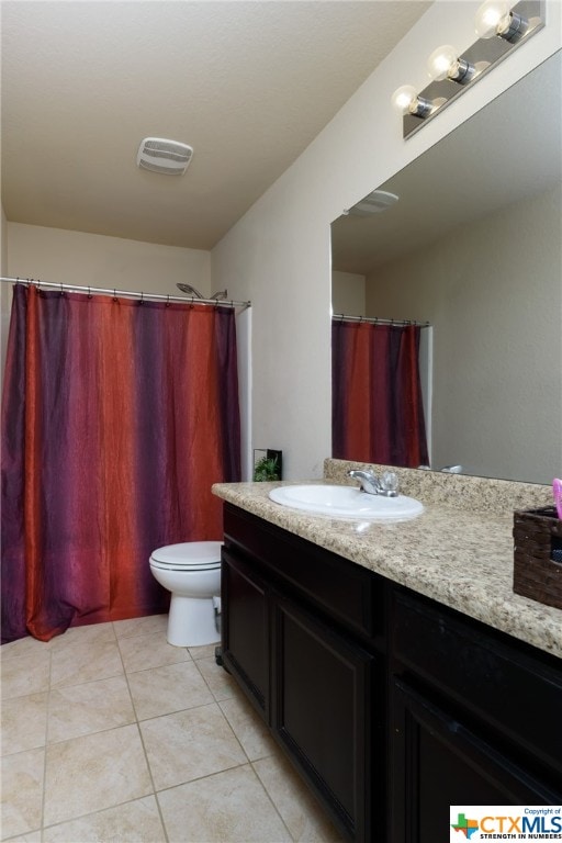 bathroom with toilet, vanity, and tile patterned floors