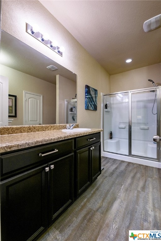 bathroom featuring a textured ceiling, an enclosed shower, vanity, and hardwood / wood-style flooring