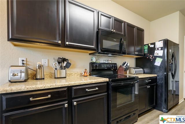 kitchen with dark brown cabinets, light hardwood / wood-style floors, black appliances, and light stone counters