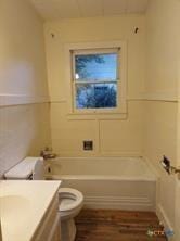 bathroom with a tub to relax in, toilet, vanity, and wood finished floors