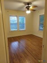 empty room featuring ceiling fan, baseboards, and wood finished floors