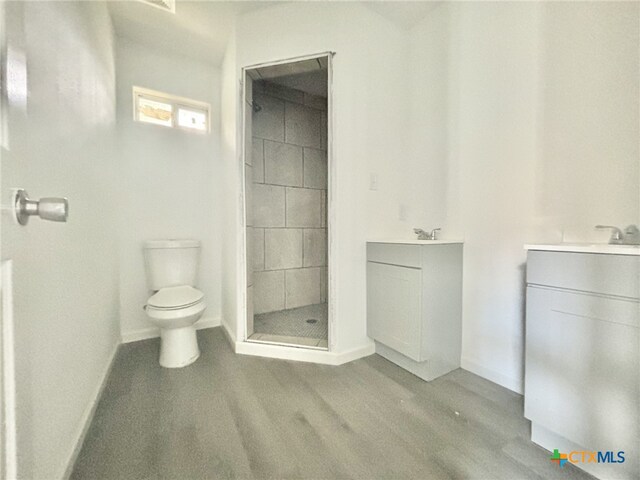 bathroom featuring hardwood / wood-style flooring, vanity, toilet, and walk in shower