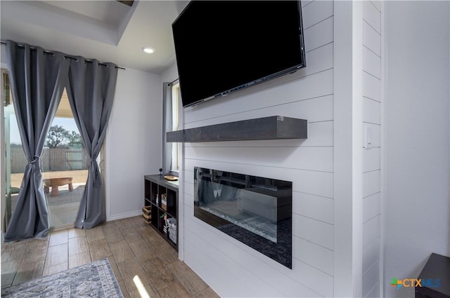 unfurnished living room featuring dark wood-style flooring, recessed lighting, a glass covered fireplace, and baseboards