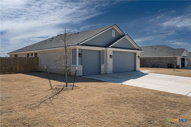 view of front facade featuring a garage, driveway, stone siding, and fence