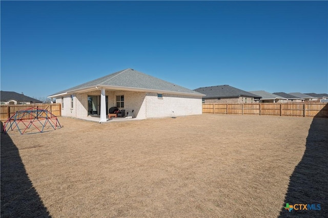 rear view of house featuring a fenced backyard, a patio, and brick siding