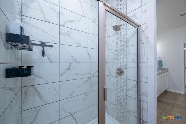 bathroom with a stall shower, vanity, and wood finished floors