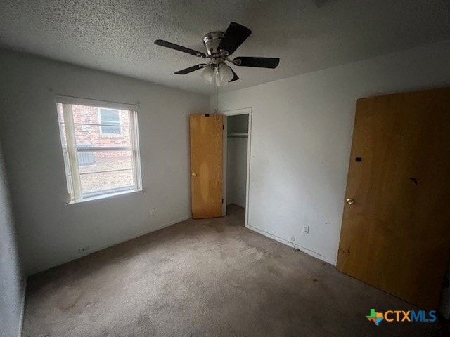 unfurnished bedroom with a textured ceiling, ceiling fan, light carpet, and a closet