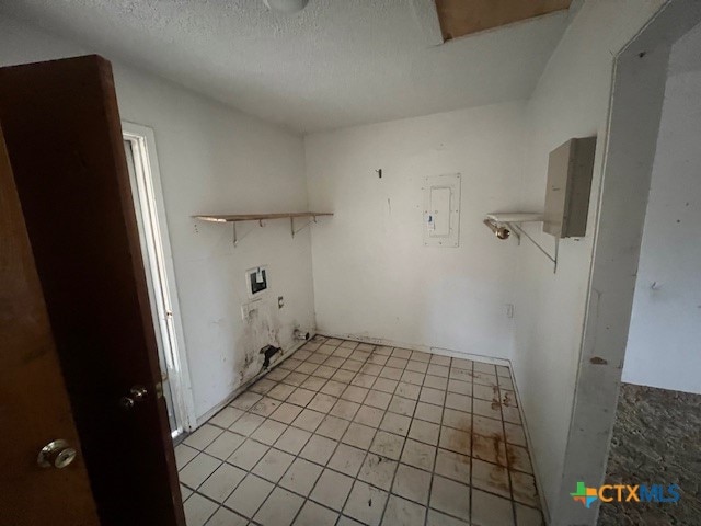 clothes washing area featuring electric panel, hookup for a washing machine, light tile patterned flooring, and a textured ceiling