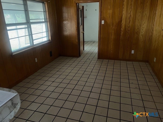 tiled empty room featuring wood walls