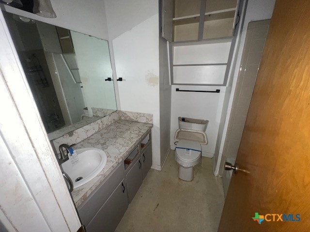 bathroom with vanity, toilet, and concrete flooring