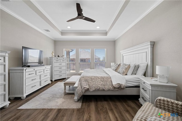 bedroom with dark wood finished floors, a raised ceiling, visible vents, ornamental molding, and a ceiling fan