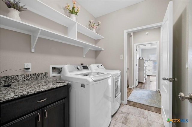 clothes washing area featuring separate washer and dryer, cabinet space, and baseboards