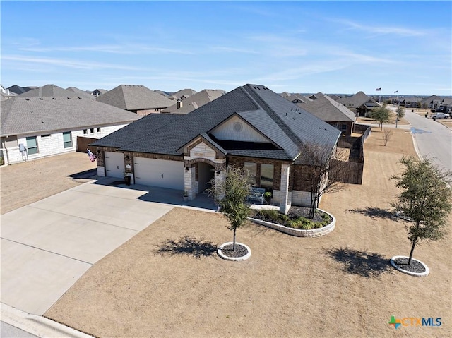 view of front of property featuring driveway, a shingled roof, stone siding, a residential view, and an attached garage