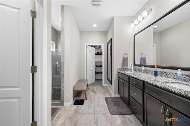 bathroom featuring double vanity, a shower stall, a spacious closet, and a sink