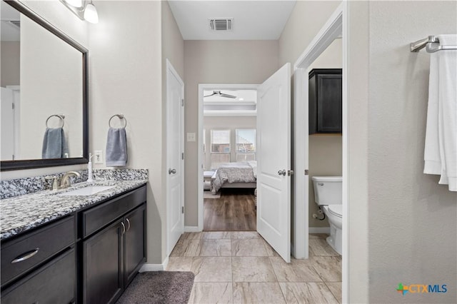 ensuite bathroom featuring visible vents, toilet, a ceiling fan, vanity, and ensuite bath