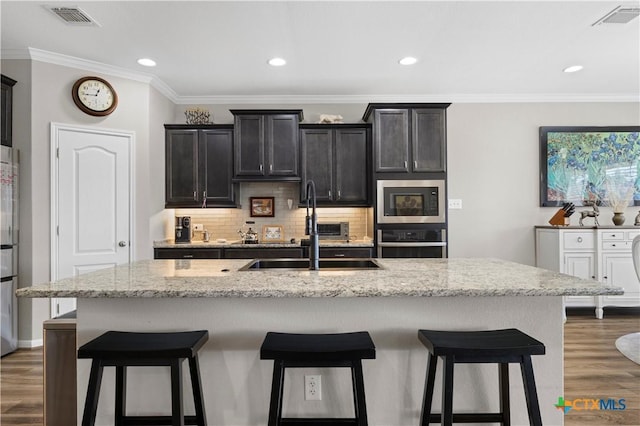 kitchen with a kitchen bar, visible vents, stainless steel appliances, and a sink