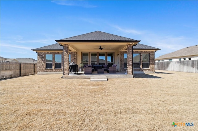 rear view of house with a fenced backyard, a patio, a ceiling fan, and brick siding