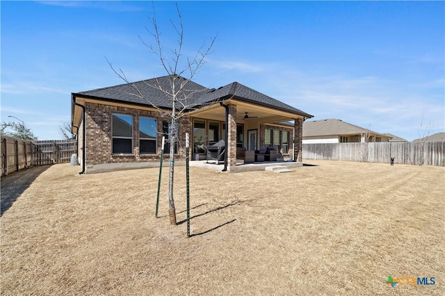 rear view of property with ceiling fan, a patio, a fenced backyard, brick siding, and roof with shingles