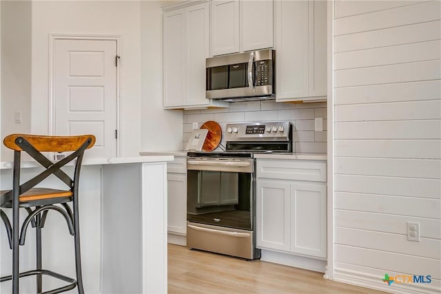 kitchen featuring decorative backsplash, white cabinets, and appliances with stainless steel finishes