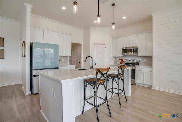 kitchen with a center island with sink, white cabinetry, and stainless steel appliances