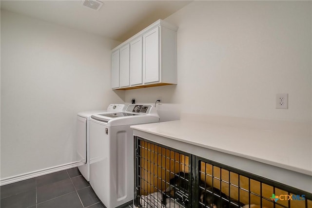 clothes washing area featuring cabinets, dark tile patterned flooring, and washer and dryer