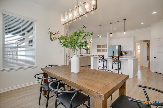 dining space featuring a healthy amount of sunlight, light wood-type flooring, and ornamental molding