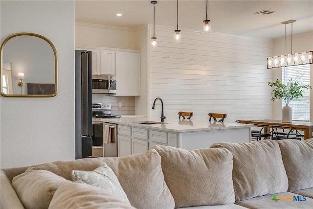 kitchen with white cabinets, decorative light fixtures, sink, and stainless steel appliances