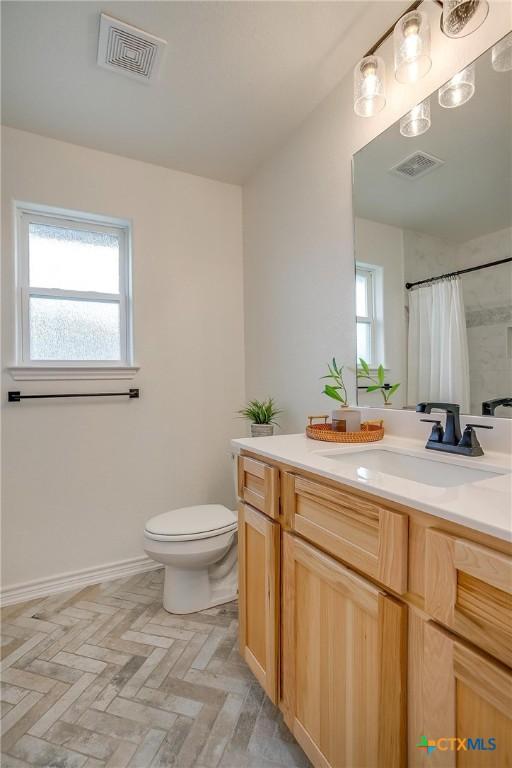 bathroom featuring vanity, toilet, and walk in shower