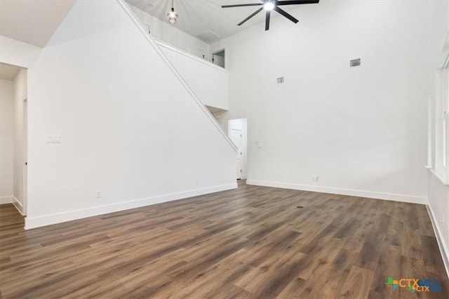 unfurnished living room with ceiling fan, dark hardwood / wood-style flooring, and a high ceiling