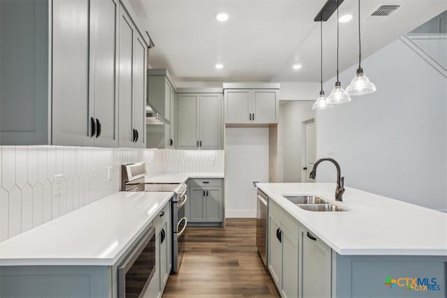 kitchen with a center island with sink, decorative light fixtures, sink, and stainless steel appliances