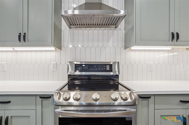 kitchen with decorative backsplash, wall chimney range hood, and stainless steel range