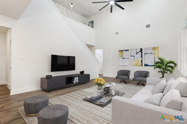 living room featuring ceiling fan, hardwood / wood-style floors, and a high ceiling